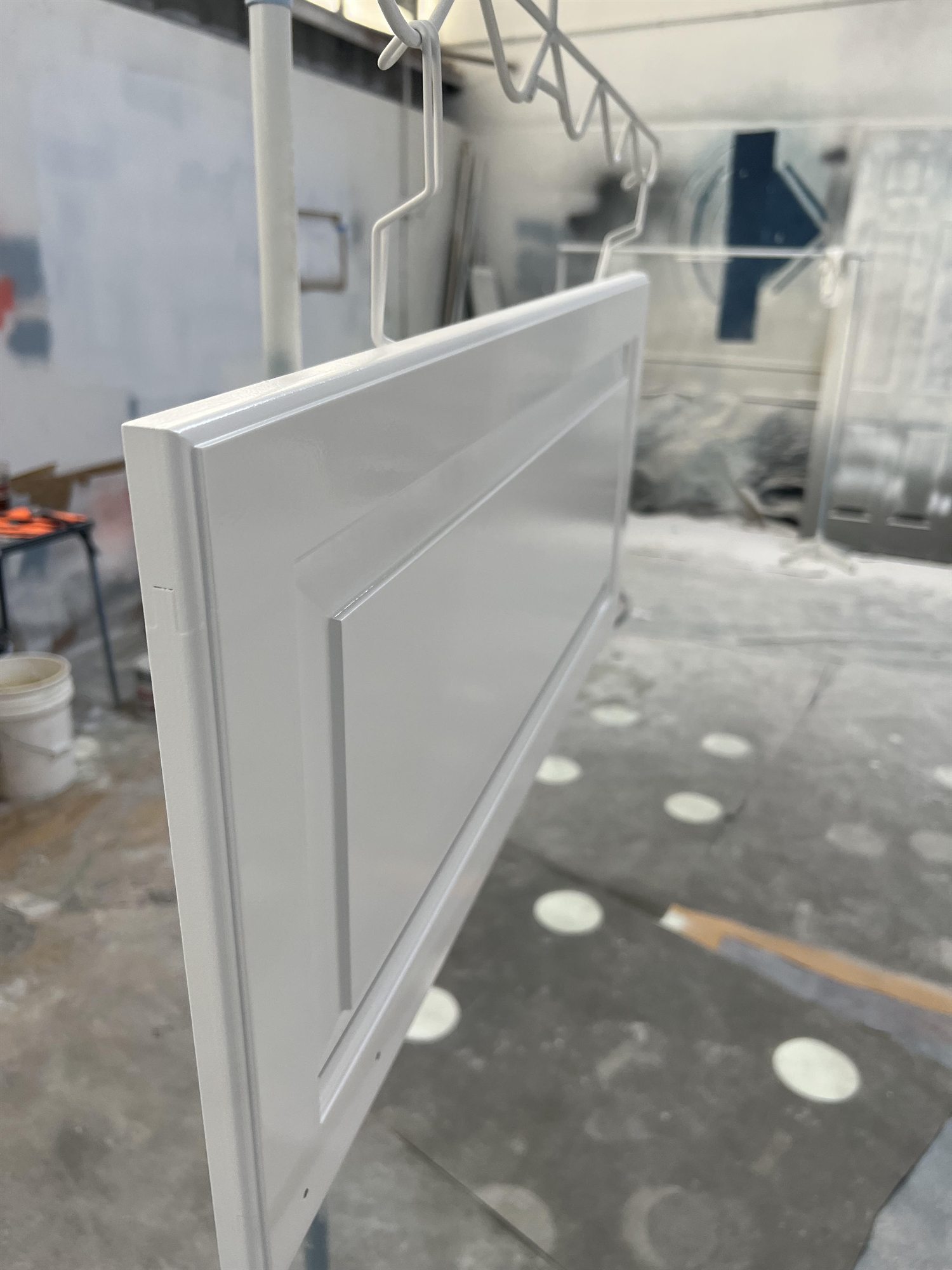 Cabinet door curing on the rack in the Vold Painting spray shop